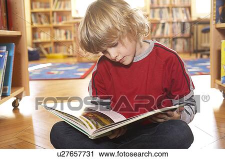 Stock Image - Boy reading a book on the floor. Fotosearch