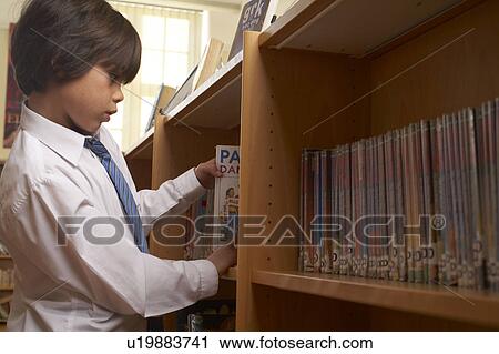 Stock Image - Boy taking books from library. Fotosearch