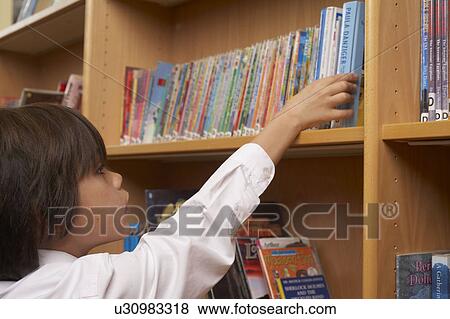 Stock Photo - Boy taking books from library. Fotosearch