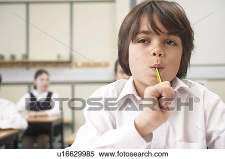 Boy with pencil in mouth, in classroom View Large Photo Image Stock Photography - Boy with pencil in mouth, in classroom. Fotosearch