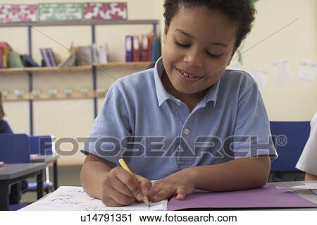 Stock Image - Boy writing in classroom. Fotosearch