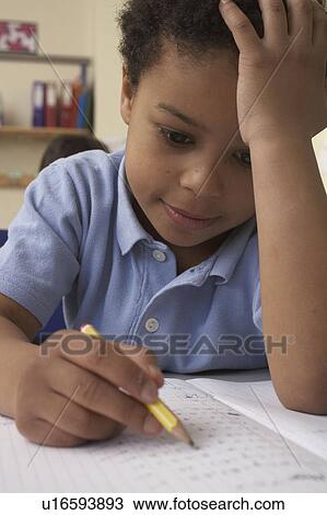 Stock Image - Boy writing in classroom. Fotosearch