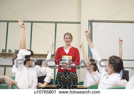 Stock Image - Children raising hands in classroom. Fotosearch