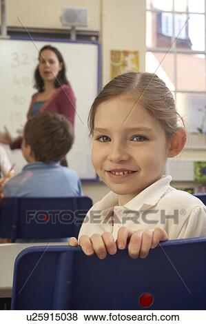 Stock Photo - Girl looking at camera, in classroom. Fotosearch
