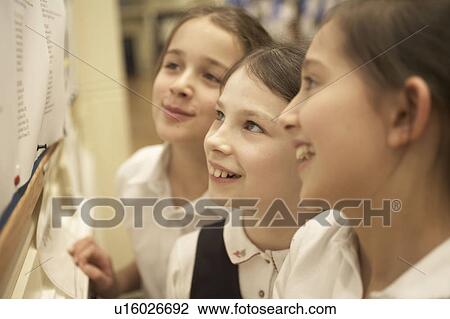 Stock Image - Girls reading message board. Fotosearch