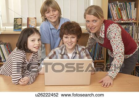 Stock Image - Group on computer, smiling. Fotosearch