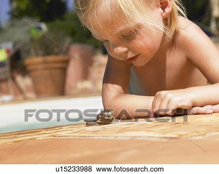 Stock Photo - Little girl looking at a snail.. Fotosearch