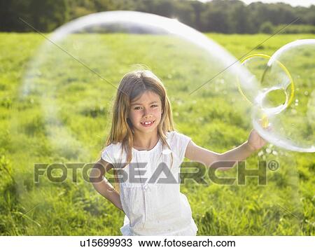 Stock Image - Little girl making soap bubbles.. Fotosearch