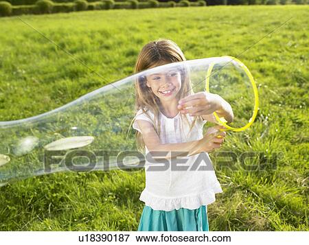 Stock Photo - Little girl making soap bubbles.. Fotosearch