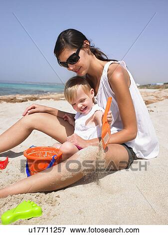 Stock Photo - Woman and young girl at the beach playing and smiling.. Fotosearch
