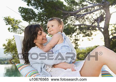 Woman holding a baby by an infinity pool smiling. View Large Photo Image Stock Photography - Woman holding a baby by an infinity pool smiling.. Fotosearch