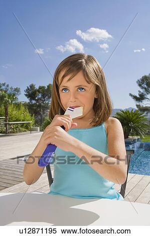 Stock Photography - Young girl eating cream with a spatula.. Fotosearch