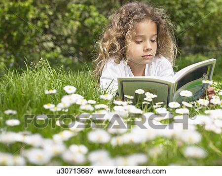 Young girl lying in the grass reading. View Large Photo Image Stock Photo - Young girl lying in the grass reading.. Fotosearch