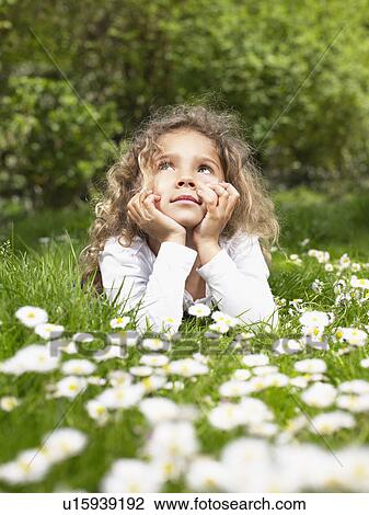 Stock Image - Young girl lying in the grass relaxing.. Fotosearch