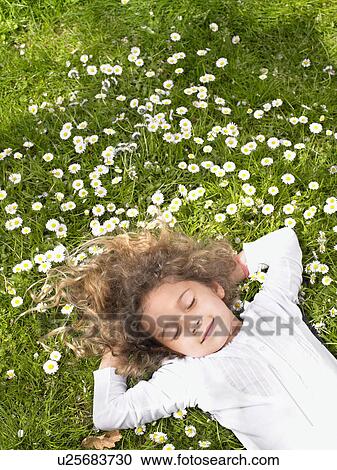 Young girl with eyes closed lying in the grass smiling. View Large Photo Image Stock Image - Young girl with eyes closed lying in the grass smiling.. Fotosearch