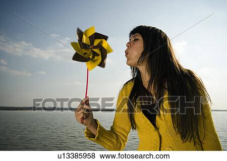 Stock Photo - Girl blowing at toy windmill.. Fotosearch