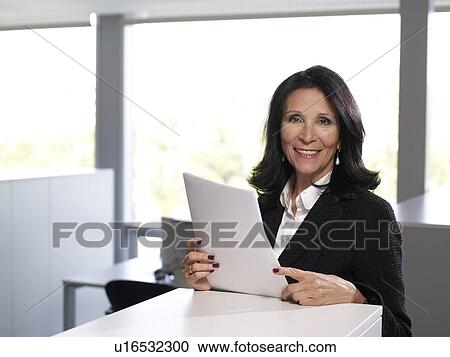 Stock Image - Senior businesswoman in office, portrait, smiling. Fotosearch