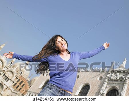 Stock Photography - Smiling woman with arms outstretched. Palazzo Ducale, Venice, Italy.. Fotosearch