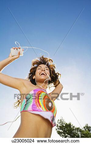 Woman dancing to MP3 Player outdoors smiling. View Large Photo Image Picture - Woman dancing to MP3 Player outdoors smiling.. Fotosearch