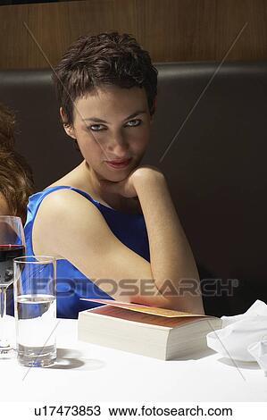 Woman flirting with camera in a restaurant with a book View Large Photo Image Stock Image - Woman flirting with camera in a restaurant with a book. Fotosearch