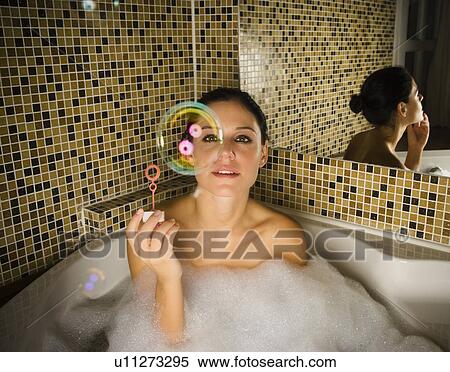 Stock Photography - Woman in bath looking at bubble.. Fotosearch