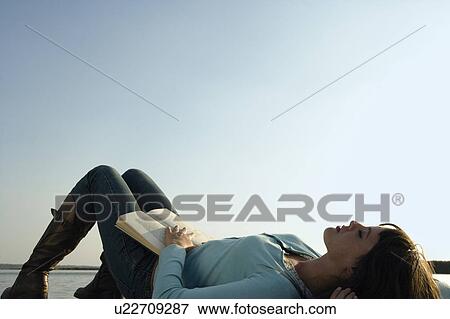 Woman lying on her back with a book. View Large Photo Image Stock Photo - Woman lying on her back with a book.. Fotosearch