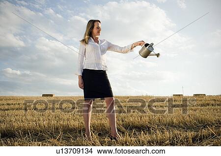 Woman pouring water on wheat field. View Large Photo Image Picture - Woman pouring water on wheat field.. Fotosearch