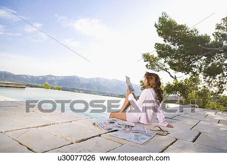 Woman relaxing by infinity pool reading newspaper. View Large Photo Image Stock Photograph - Woman relaxing by infinity pool reading newspaper.. Fotosearch