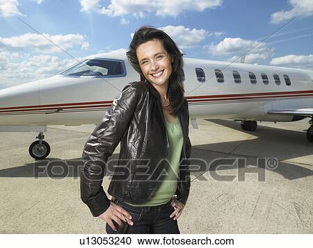 Stock Image - Woman standing next to private jet.. Fotosearch