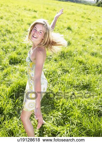 Stock Photo - Young woman dancing in a green field.. Fotosearch