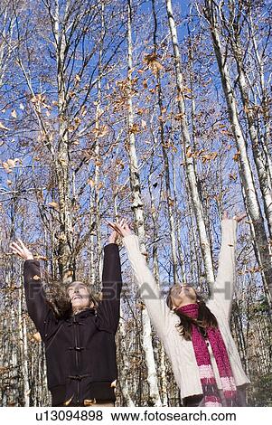 Stock Photo - 2 young woman throwing leaf in the air.. Fotosearch