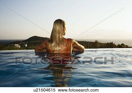 Stock Photography - Woman leaning at the ledge of an infinity pool.. Fotosearch