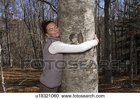 Stock Image - Woman taking a tree in her arms.. Fotosearch