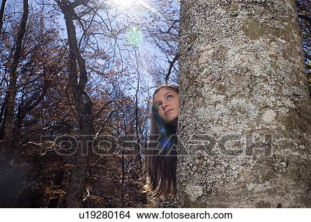 Young woman hiding behind a tree. View Large Photo Image Picture - Young woman hiding behind a tree.. Fotosearch