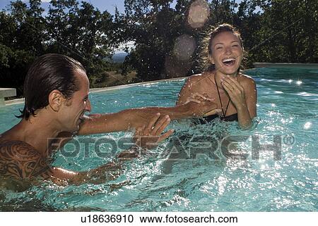 Couple playing with water in the swimming pool View Large Photo Image Stock Image - Couple playing with water in the swimming pool. Fotosearch