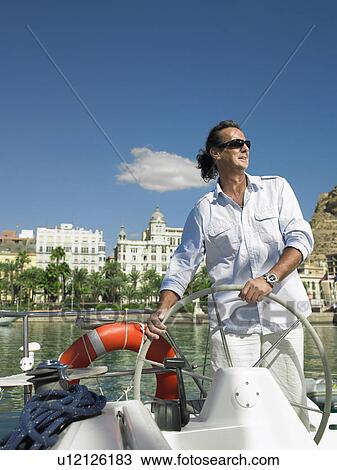 Mature man wearing sunglasses steering yacht, smiling View Large Photo Image Stock Image - Mature man wearing sunglasses steering yacht, smiling. Fotosearch