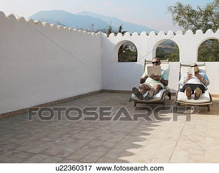 Senior couple relaxing on sun loungers, reading View Large Photo Image Stock Photo - Senior couple relaxing on sun loungers, reading. Fotosearch