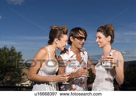 Stock Photo - Three people with drinks outdoors. Fotosearch