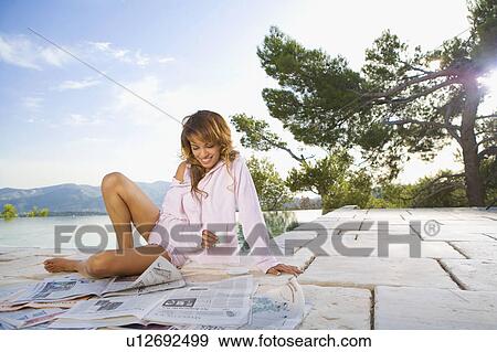 Woman by infinity pool reading newspaper and smiling. View Large Photo Image Stock Photo - Woman by infinity pool reading newspaper and smiling.. Fotosearch