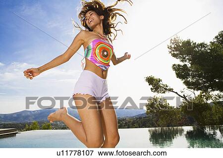 Woman jumping near an inifinity pool smiling. View Large Photo Image Stock Photo - Woman jumping near an inifinity pool smiling.. Fotosearch