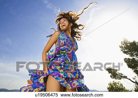 Stock Photography - Woman laughing outdoors in a colorful dress.. Fotosearch