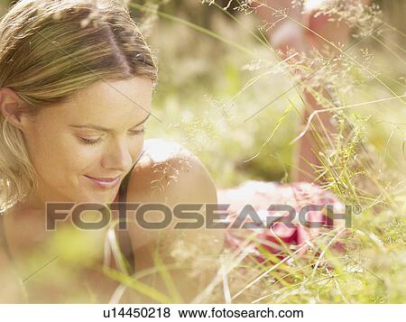 Stock Photo - Woman lying in grass smiling.. Fotosearch