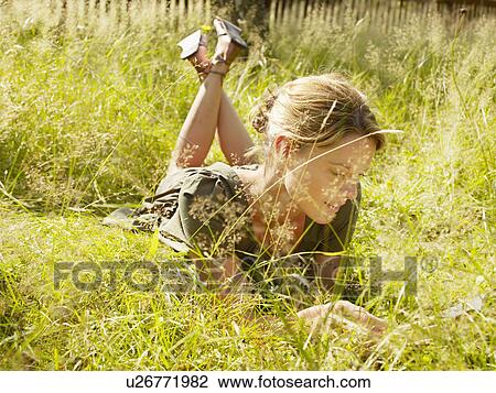 Woman lying in the grass reading. View Large Photo Image Stock Image - Woman lying in the grass reading.. Fotosearch