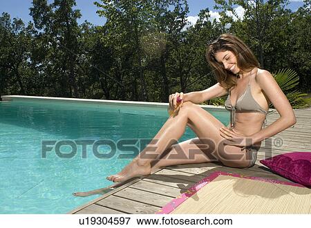 Woman on a wood deck by a swimming pool with sunscreen View Large Photo Image Stock Photo - Woman on a wood deck by a swimming pool with sunscreen. Fotosearch
