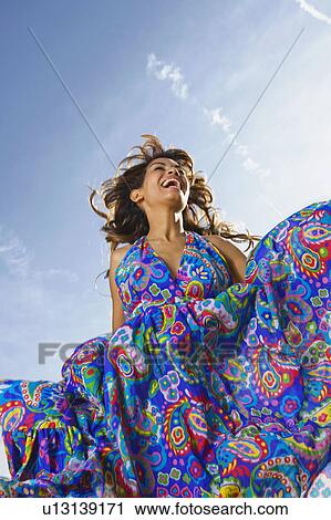 Stock Image - Woman outdoors laughing in a colorful dress.. Fotosearch