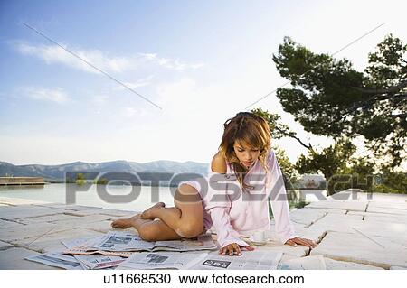 Woman relaxing by infinity pool reading newspaper. View Large Photo Image Stock Image - Woman relaxing by infinity pool reading newspaper.. Fotosearch