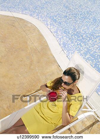 Woman relaxing on sun lounger by pool View Large Photo Image Stock Image - Woman relaxing on sun lounger by pool. Fotosearch