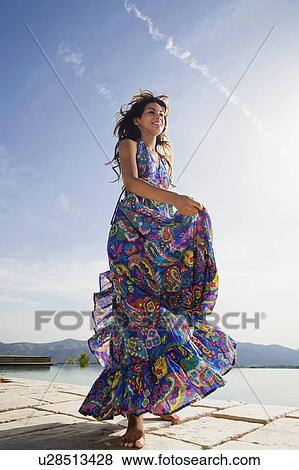 Woman smiling by an infinity pool in a colorful dress. View Large Photo Image Stock Photo - Woman smiling by an infinity pool in a colorful dress.. Fotosearch