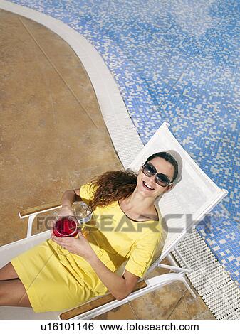 Woman wearing sunglasses relaxing on sun lounger, smiling View Large Photo Image Stock Photograph - Woman wearing sunglasses relaxing on sun lounger, smiling. Fotosearch
