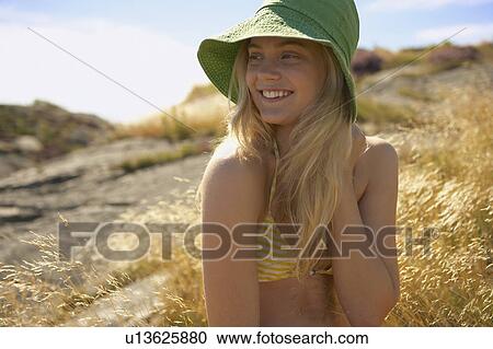 Stock Image - Young Woman Sitting in Long grass.. Fotosearch
